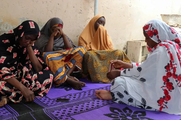 نساء ينتحبن على مقتل أحد عمال الإغاثة الذين أعدمهم مسلحون إرهابيون في مدينة مايدوغوري شمال شرقي نيجيريا في 23 يوليو 2020 (رويترز)