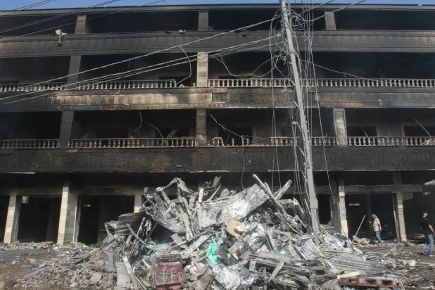 People inspect the destruction outside a charred building hit by an Israeli airstrike in the southern Lebanese town of Wadi Jilo, east of Tyre, on June 6, 2024. (AFP)
