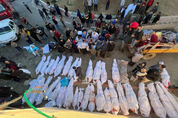 أشخاص يتجمعون بالقرب من جثث فلسطينيين قتلوا في غارات إسرائيلية بغزة (رويترز)