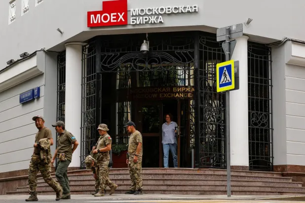 أشخاص يسيرون بالقرب من بورصة موسكو (رويترز)