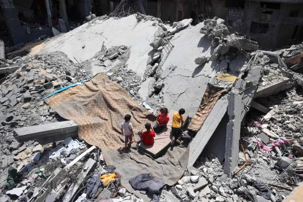 أطفال يلعبون فوق أبنية مدمرة في مخيم النصيرات بوسط قطاع غزة السبت (أ.ف.ب)