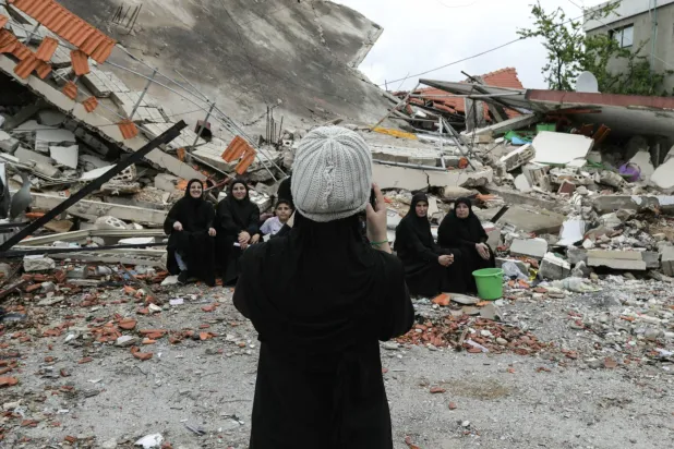 لبنانيات يلتقطن صورة إلى جانب منزل مدمَّر بغارة إسرائيلية في بلدة عيتا الشعب بالجنوب (أ.ف.ب)