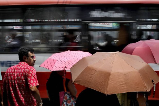 Indian commuters use umbrellas during a hot afternoon in Kolkata, India, 14 June 2024. (EPA)