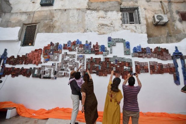 Tunisians react as they attend the inauguration of “1001 Bricks Fresco”, a participatory artwork by more than 500 inhabitants of Tunis led by Swiss artist Anne Francey, illustrating the diversity of the city, with the bas relief installed on the edge of the medina, the old town listed by UNESCO, in the capital's El-Hafsia district on June 7, 2024. (Fethi Belaid / AFP) 