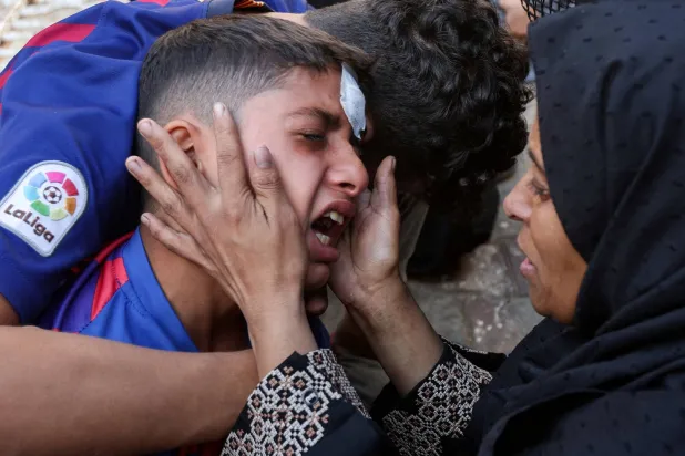 تواسي فتى خلال تشييع ضحايا غارة إسرائيلية في دير البلح اليوم الثلاثاء (رويترز)