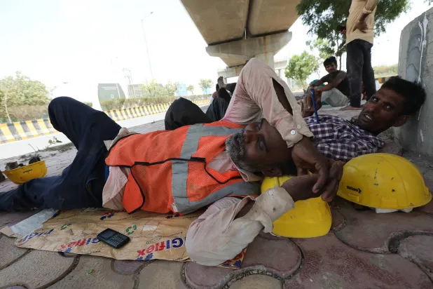 عمال هنود يستريحون في الظل هرباً من الحر قرب العاصمة نيودلهي أمس (إ.ب.أ)