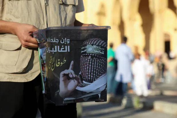 فلسطيني يحمل صندوق تبرعات لضحايا حرب غزة خلال حملة نظمتها «حماس» في عيد الأضحى (رويترز)