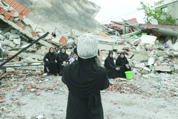 Lübnanlı kadınlar, güneydeki Aita al-Shaab kasabasında İsrail baskını sırasında yıkılan bir evin yanında fotoğraf çekiyor (AFP)
