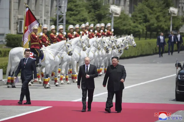 Putin, Pyongyang'daki Kim İl-sung Meydanı'nda düzenlenen resmi karşılama töreni sırasında Kim'in yanında yürürken (AP)