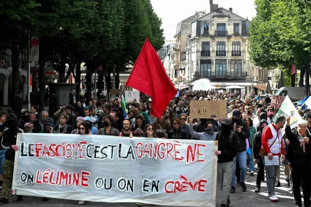 متظاهرون يحملون لافتة كُتب عليها «الفاشية غرغرينا - اقتلوها أو موتوا بها» خلال مسيرة مناهضة لليمين المتطرف بعد أن دعا الرئيس الفرنسي إلى انتخابات تشريعية بعد المكاسب الكبيرة التي حققتها أحزاب اليمين المتطرف في انتخابات البرلمان الأوروبي (أ.ف.ب)