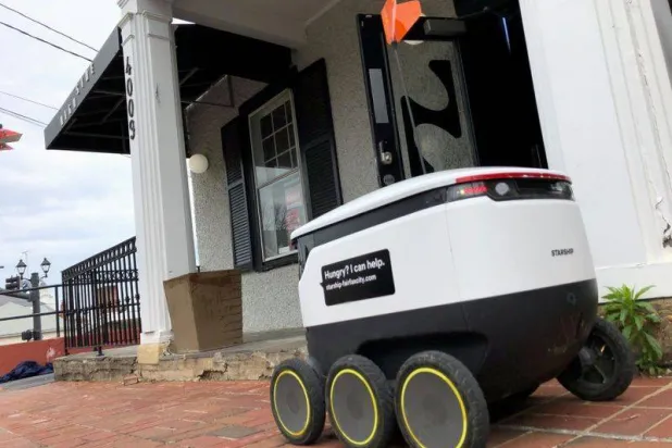 روبوت يقوم بتوصيل طلبات خارج أحد المحال في ولاية فيرجينا الأميركية وقت تفشي «كورونا» (أرشيفية- رويترز)