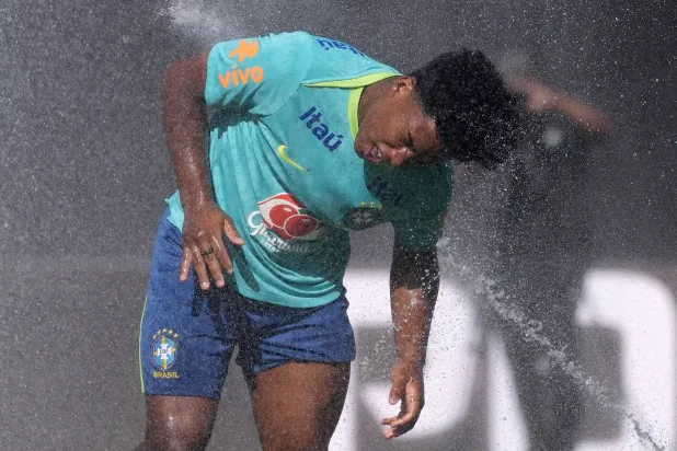 إندريك يلهو برذاذ الماء خلال تدريبات البرازيل (أ.ب)