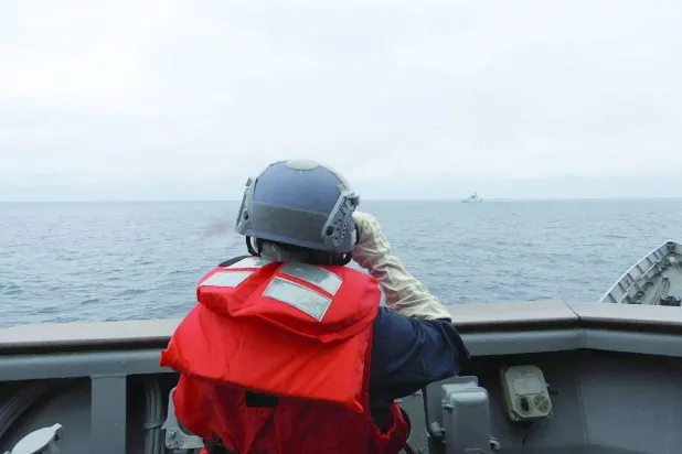 أحد أفراد القوات المسلحة التايوانية يراقب سفينة عسكرية صينية قبالة سواحل تايوان (أرشيفية - أ.ف.ب)