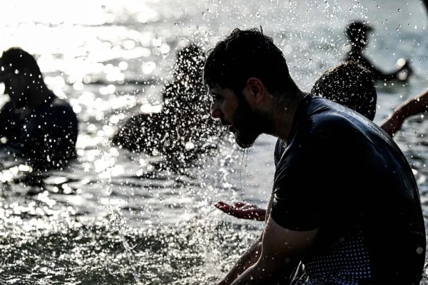 عراقي يلطف من الحرارة المرتفعة بمياه نهر شط العراق جنوب البصرة (أ.ف.ب)