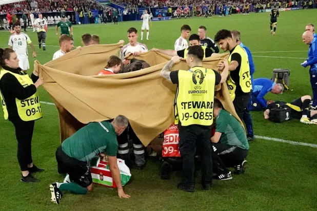 فارغا لاعب منتخب المجر يتلقى الإسعافات الأولية خلف الساتر على أرضية ملعب المباراة (رويترز)