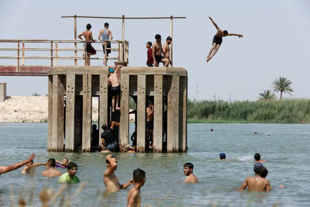 عراقيون يسبحون في نهر الفرات بمدينة النجف في ظل ارتفاع درجات الحرارة في العراق يوم 21 يونيو الجاري (رويترز)