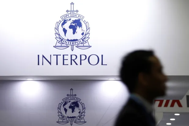 رجل يمر عبر لافتات «الإنتربول» في معرض «الإنتربول» العالمي بسنغافورة في 2 يوليو 2019 (رويترز)