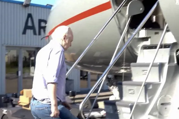 جوليان أسانج يصعد إلى الطائرة التي أقلته من لندن إلى بانكوك الاثنين (أ.ف.ب)