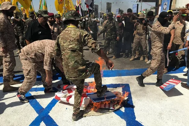 Members of a pro-Iran Iraq faction burn an Israeli flag during a rally in Baghdad. (AP) 