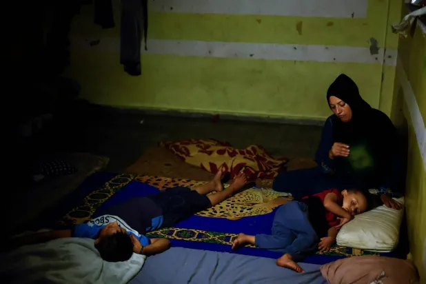 أمل نصير بمعية أطفالها داخل إحدى مدارس الأمم المتحدة في خان يونس 25 يونيو 2024 (رويترز)