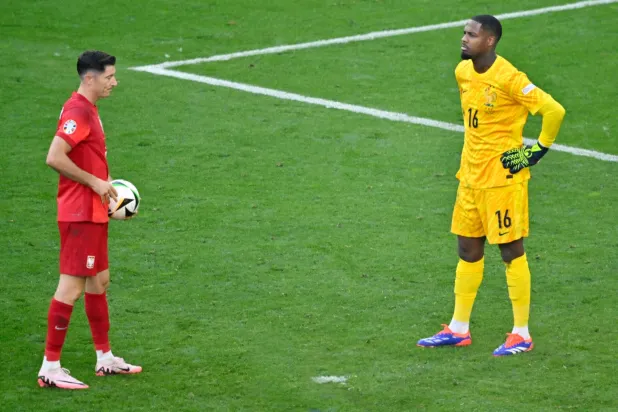 ماينان حارس مرمى فرنسا بدا غاضباً من أسلوب النجم البولندي ليفاندوفسكي مع ضربة الجزاء (أ.ف.ب)