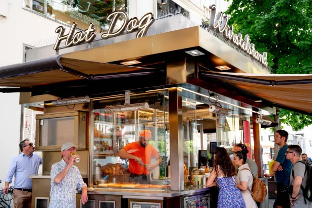 يصطف الزبائن خارج كشك النقانق في فيينا (أ.ف.ب)