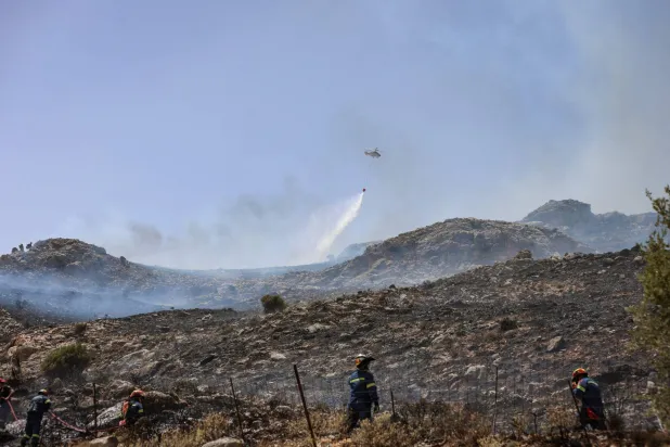طائرة مروحية ترش الماء للمساهمة في إطفاء حرائق بجزيرة كريت اليونانية (أ.ف.ب)