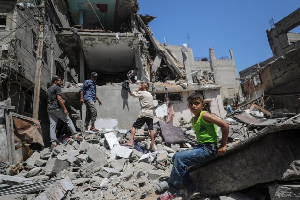 A child looks on as Palestinians search for missing people under the rubble of a destroyed house following an Israeli air strike, at al-Nuseirat refugee camp, southern Gaza Strip, 18 June 2024. (EPA) 