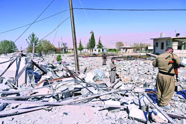 مقاتلون يعاينون آثار القصف الإيراني على السليمانية بكردستان العراق في سبتمبر العام الماضي (إ.ب.أ)