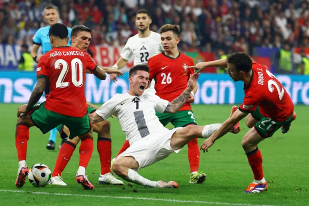 فيربيتش لاعب سلوفينيا (وسط) تحت الرقابة اللصيقة من لاعبي البرتغال خلال مواجهة دور الـ16 في «اليورو» (رويترز)