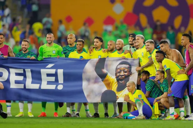 لاعبو المنتخب البرازيلي يحملون لافته عليها أسطورة البرازيل بيليه في إحدى المناسبات الرياضية (أ.ف.ب)