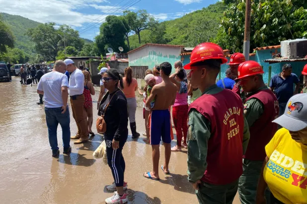 سكان وعناصر الإنقاذ يقفون في شارع غمرته المياه عقب مرور إعصار بيريل على الطريق من كومانا إلى كوماناكوا بولاية سوكري بفنزويلا (أ.ف.ب)