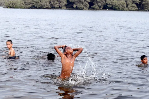 أطفال يستحمّون في ترعة (د.ب.أ)