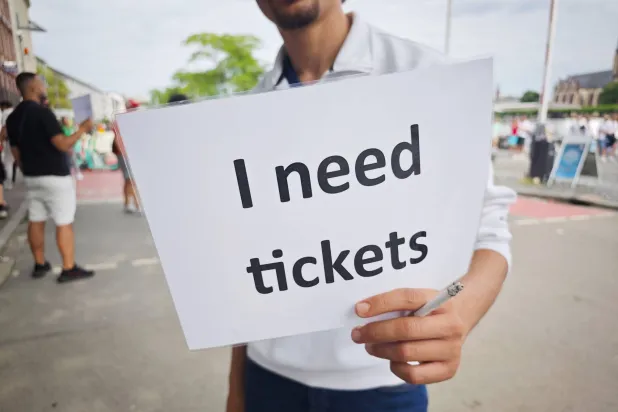 أحد الجماهير يسير حاملاً لافتة كتب عليها «أحتاج إلى تذاكر» رغم تحذيرات الاتحاد الأوروبي (د.ب.أ)