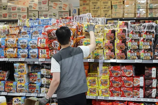 عامل في أحد المحال التجارية بكوريا الجنوبية يضع أكياس المعكرونة سريعة التحضير على الأرفف (وكالة يونهاب الكورية الجنوبية)