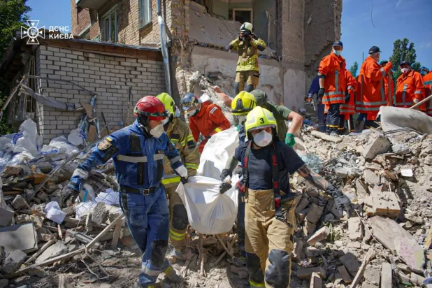 رجال إنقاذ يحملون جثة شخص عُثر عليها تحت الأنقاض في الموقع الذي ضُرب فيه مبنى سكني بصاروخ روسي وسط هجوم روسيا على أوكرانيا بكييف (رويترز)