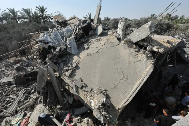 فلسطينيون يتفقدون منزلًا دمر في غارة إسرائيلية في مخيم النصيرات للاجئين وسط قطاع غزة (رويترز)