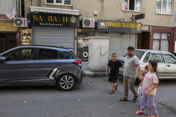 People walk past closed shops in Hocahasan district, mostly populated by Syrians, in Bursa, western Türkiye, Tuesday, July 2, 2024. (Ugur Yildirim/Dia Photo via AP)
