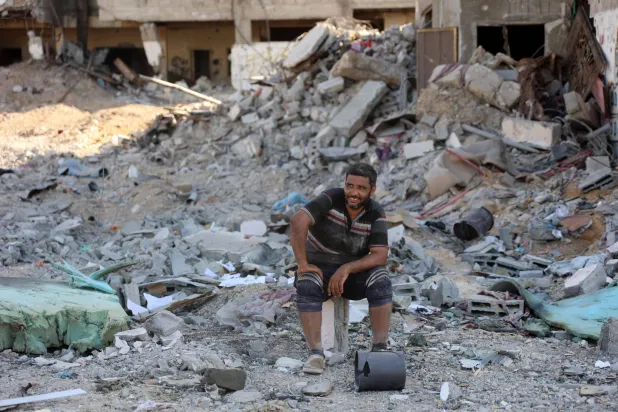 فلسطيني يجلس وسط الركام يوم الأربعاء بعد قصف حي الشجاعية شرق قطاع غزة (أ.ف.ب)