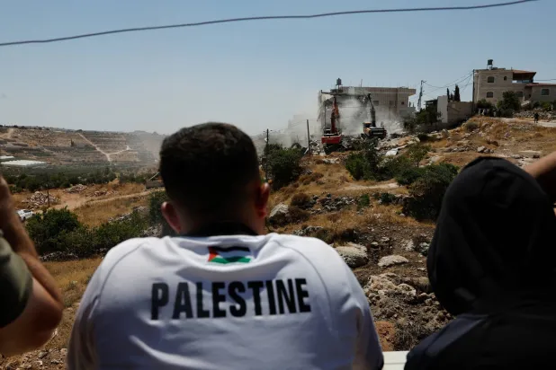 فلسطينيون يشاهدون تجريف أراض وتدمير منازل في الضفة الغربية (رويترز)