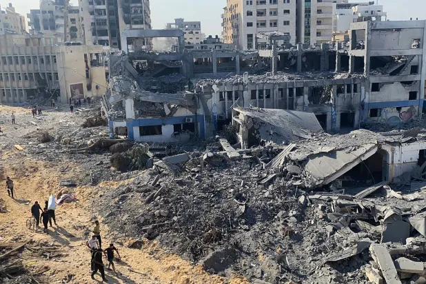 فلسطينيون وسط الدمار في أحد أحياء غزة (د.ب.أ)