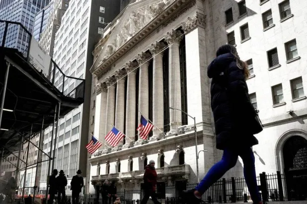 مشاة يسيرون في شارع وول ستريت أمام بورصة نيويورك الأميركية (رويترز)
