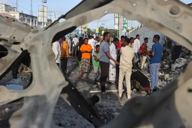 أشخاص ينظرون إلى الأضرار التي لحقت بموقع هجوم بالقنابل في مقديشو 15 يوليو 2024 قُتل تسعة أشخاص وأصيب أكثر من 20 آخرين (أ.ب.أ)