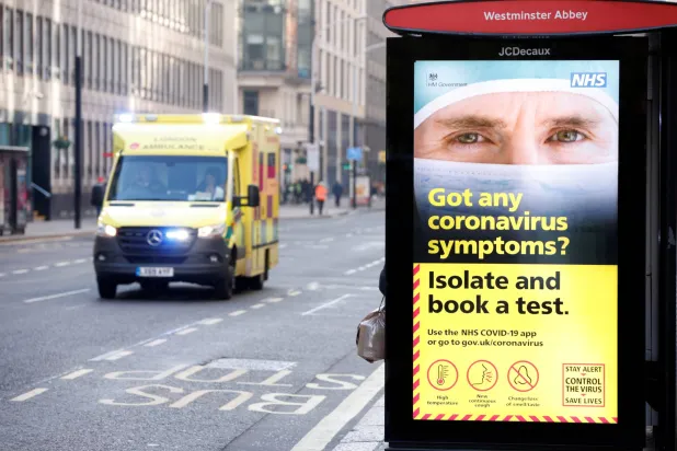 سيارة إسعاف تمر أمام لافتة توضح الإجراءات التي فرضتها الحكومة ضد تفشي مرض فيروس كورونا في لندن (أرشيفية - رويترز)