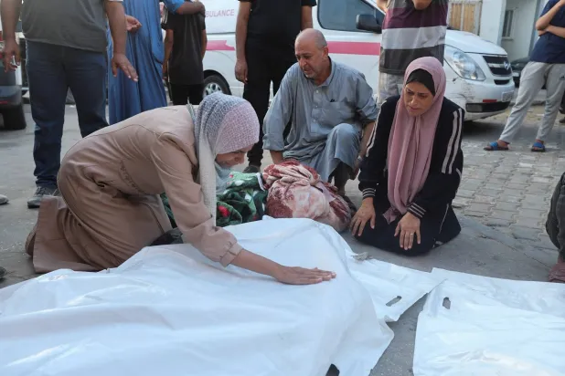 جثة مغطاة لأحد الفلسطينيين قُتل في غارات إسرائيلية في دير البلح وسط قطاع غزة (رويترز)