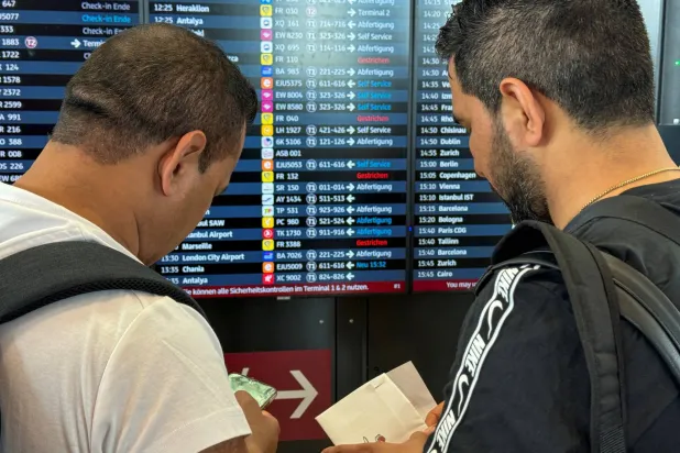 مسافرون ينظرون إلى لوحة زمنية بعد انقطاع عالمي لتكنولوجيا المعلومات في مطار برلين (رويترز)