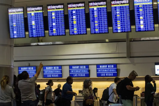 ركاب يتحققون من شاشات المغادرة والوصول مع تأخر الرحلات الجوية بسبب انقطاع التكنولوجيا العالمية في مطار أميركي (أ.ب)