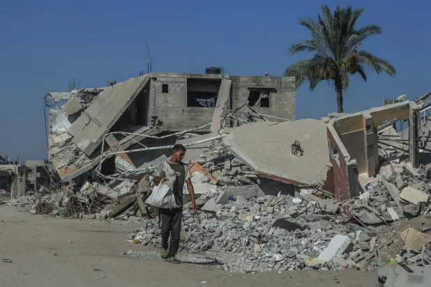 فلسطيني يسير بجوار الدمار في خان يونس بقطاع غزة (د.ب.أ)