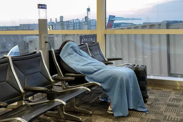 مسافر يستريح في مطار مقاطعة ديترويت ميتروبوليتان واين بانتظار إعادة جدولة الرحلات (أ.ف.ب)