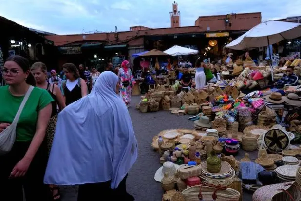 سياح وسكان محليون أثناء زيارة لسوق بالمدينة القديمة في مراكش (رويترز)